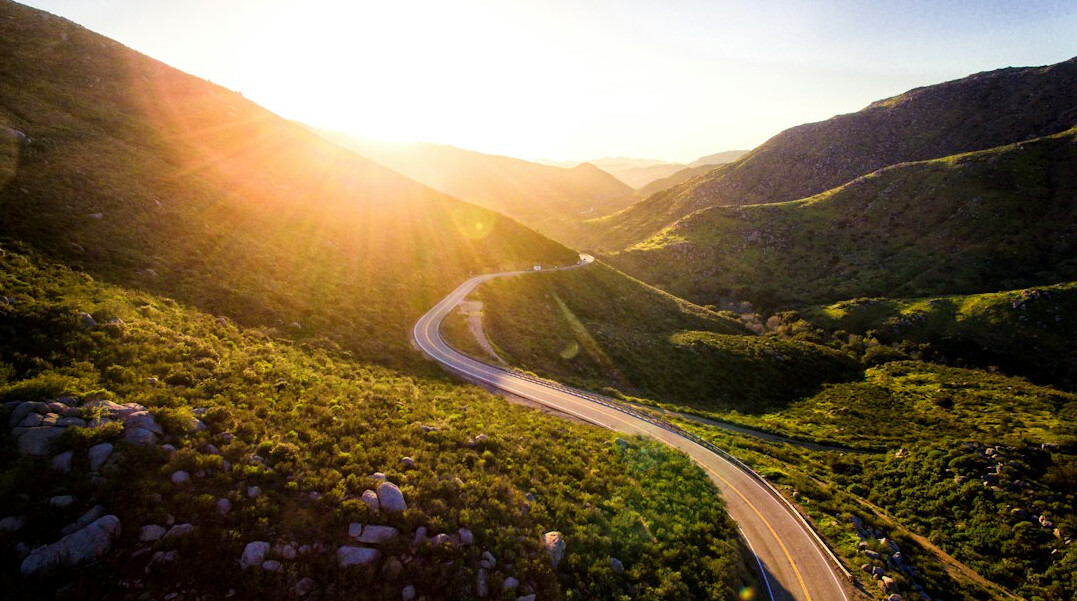 Rolling green hills with a road at sunset